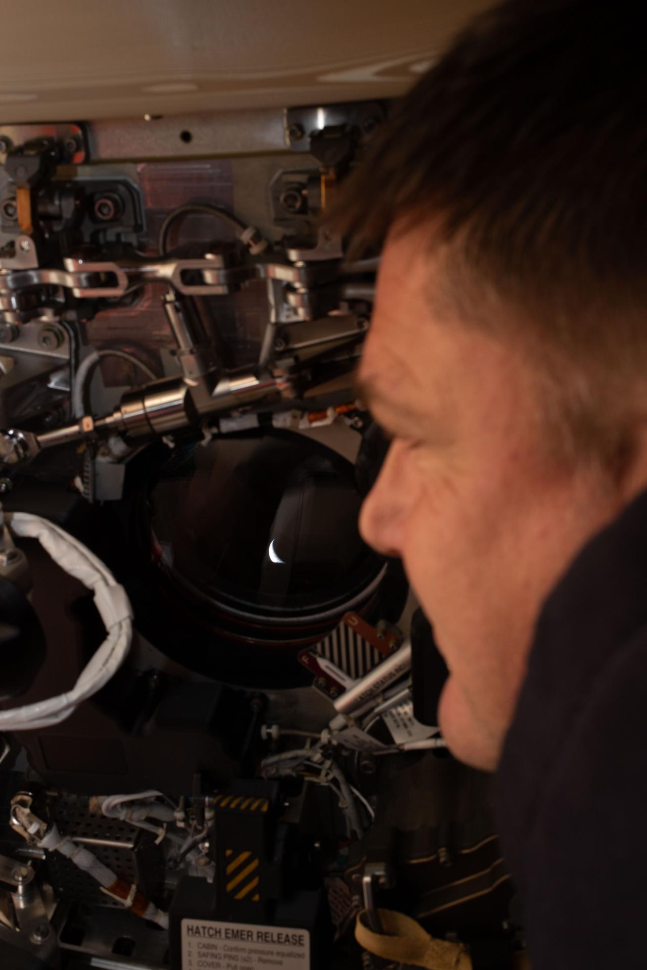 Artemis II mission specialist and CSA (Canadian Space Agency) astronaut Jeremy Hansen peers out one of the Orion spacecraft's windows looking back at Earth ahead of the crew's lunar flyby on April 6, 2026.