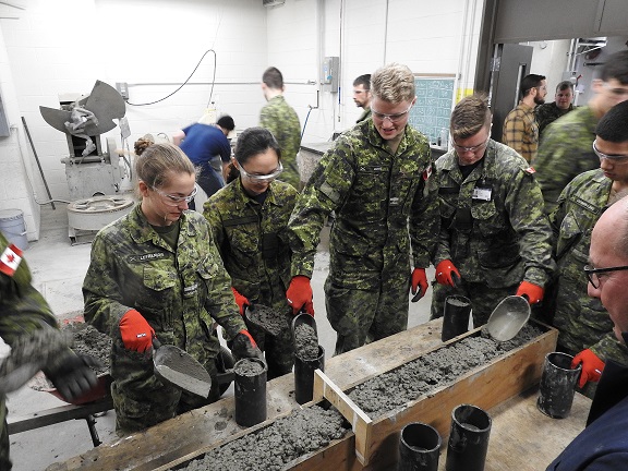 Structures Technologist and Undergraduate Students pouring Concrete test cylinders/Technologue en structures et étudiants de premier cycle coulant des cylindres d'essai en béton